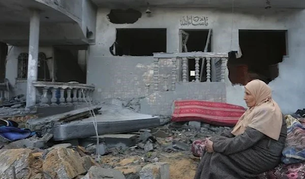 A Palestinian woman sits by houses destroyed in the Israeli bombardment of the Gaza Strip in Rafah on November 20,2023. (AP)