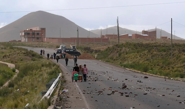 People walk on the shoulder of a road blocked by supporters of former President Evo Morales in Caracollo, Bolivia, Friday, Feb. 2, 2024. (AP)