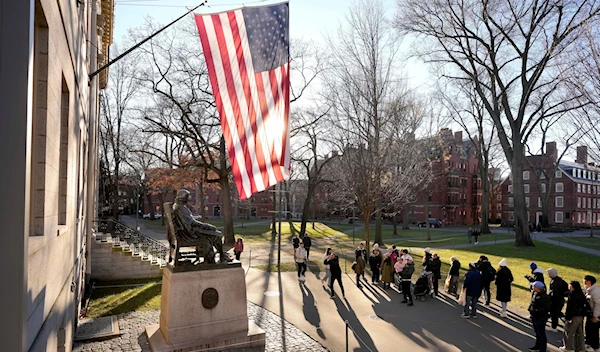 People take photographs near a John Harvard statue, left, Tuesday, Jan. 2, 2024, on the campus of Harvard University, in Cambridge, Massachusetts (AP)