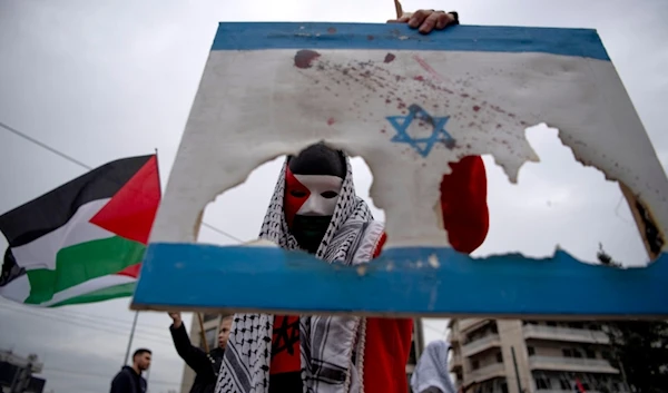 A man holds a burned Israeli flag, during a protest in front of the Israeli Embassy in Athens, Greece, Saturday, Jan. 27, 2024. (AP)