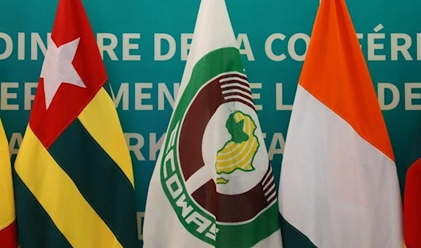 An ECOWAS flag is seen placed amid flags of member states at the bloc’s extraordinary summit on the political situation in Burkina Faso, Guinea and Mali, in Accra, Ghana on February 3, 2022. (AP)