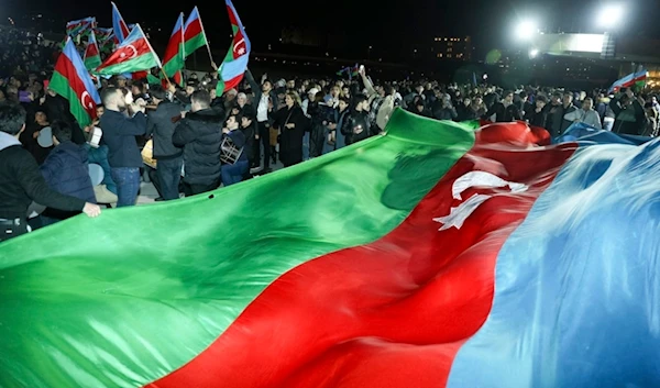 People carry a huge national flag celebrating Azerbaijan's President Ilhan Aliyev's victory in the presidential election in Baku, Azerbaijan, Wednesday, Feb. 7, 2024. (AP)