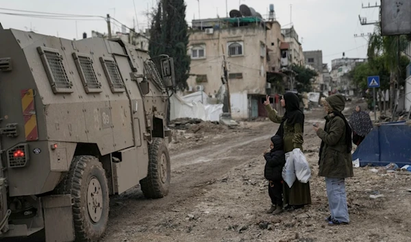 A Palestinian woman flashes a V-sign towards Israeli troops during an army raid in the Tulkarm refugee camp, West Bank, Palestine, Wednesday, Jan.17, 2024. (AP)