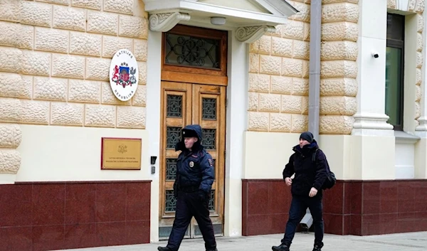 A Russian police officer and a man walk at the Latvian Embassy's building in Moscow, Russia, Tuesday, Jan. 24, 2023. (AP)