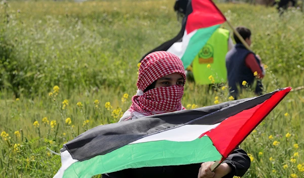 Palestinians wave flags during a rally marking the 47th anniversary of Land Day, east of Gaza City, occupied Palestine, March 30, 2023 (AP)