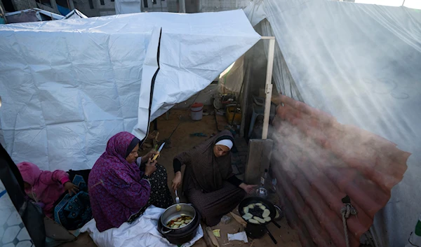 Randa Baker, Right, who was displaced by the Israeli bombardment of the Gaza Strip, prepares the Iftar meal with her mother on the first day of Ramadan at a makeshift tent camp in the al-Mawasi area, southern Gaza, March 11, 2024. (AP)