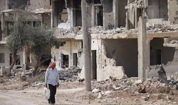 A man walks past destroyed buildings in an opposition-held neighbourhood of the southern city of Daraa, on 2 October 2018 (AFP)