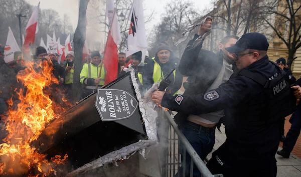 A police officer stops a protester by a burning coffin during a protest in Warsaw, Poland, on Wednesday, March 6, 2024. (AP)