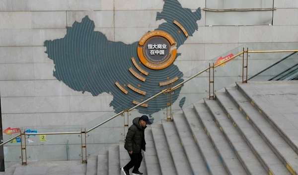 A man walks past a depiction of Evergrande properties across a China map at a partially shuttered Evergrande commercial complex in Beijing, Monday, Jan. 29, 2024. (AP)