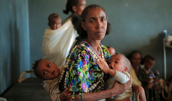 Ada Arae Girmay, 40, holds her babies Assefa and Metkel at the Finarwa Health Center in Nebar Hadnet, in the Tigray region of northern Ethiopia, on Tuesday, Feb. 27, 2024. (AP Photo/Amir Aman Kiyaro)