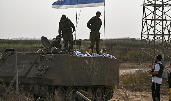 Israeli occupation forces on an armored vehicle speak with an ultra-Orthodox Haredi jew as they deploy near occupied territories bordering Gaza Strip on October 24, 2023. (AFP)