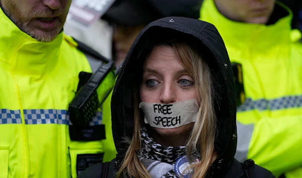 A protester stands outside the Royal Courts of Justice in London, Wednesday, Feb. 21, 2024. (AP)