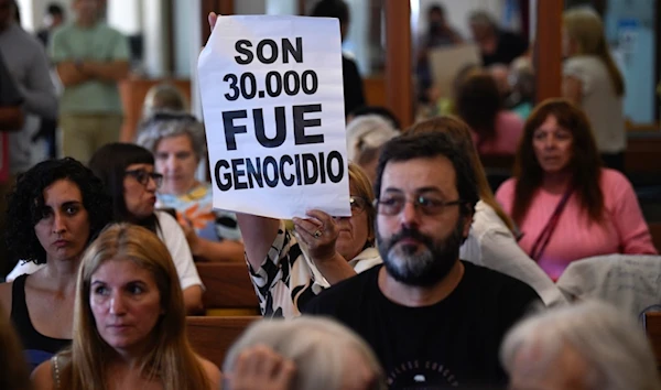 A person holds up a sign that reads: "They are 30,000. It was genocide," in court where the public listens to the verdict for former police officers on trial for crimes against humanity during the 1976-1983 dictatorship, Tuesday, March 26, 2024 (AP)