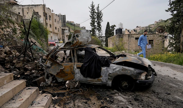 A man passes by a car destroyed by an IOF raid in the occupied West Bank in Jenin refugee camp on Wednesday, March 27, 2024. (AP)