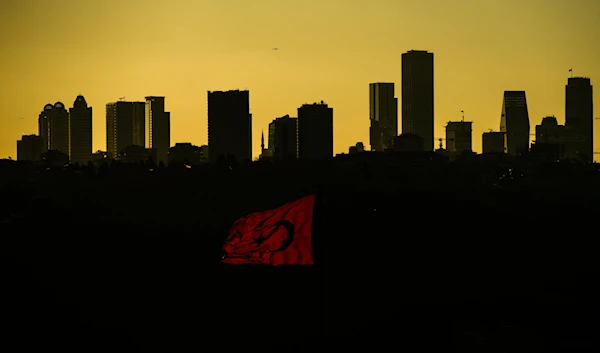 The sun sets behind high buildings of a financial business area in Istanbul, Turkey, Friday, March 22, 2024. (AP)