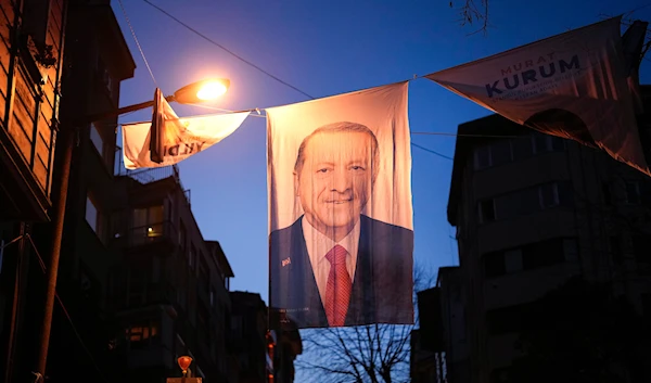 People walk under a campaign banner of Turkish President and leader of the Justice and Development Party, or AKP, Recep Tayyip Erdogan, in Istanbul, Turkey, Friday March 29, 2024. (AP)