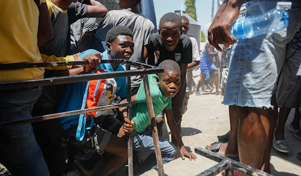 Youth take cover after hearing gunshots at a public school that serves as a shelter for people displaced by gang violence, in Port-au-Prince, Haiti on March 22, 2024. (AP)