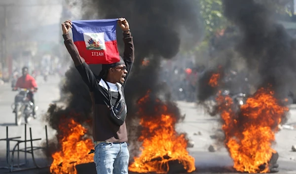 A demonstrator holds up an Haitian flag during protests demanding the resignation of Prime Minister Ariel Henry in Port-au-Prince, Haiti, Friday, March 1, 2024. (AP)