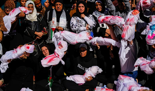 Women cradle mock bodies of dead Palestinian children wrapped in blood-stained blankets, during a sit-in in Beirut, Lebanon, Friday, Nov. 17, 2023. (AP)