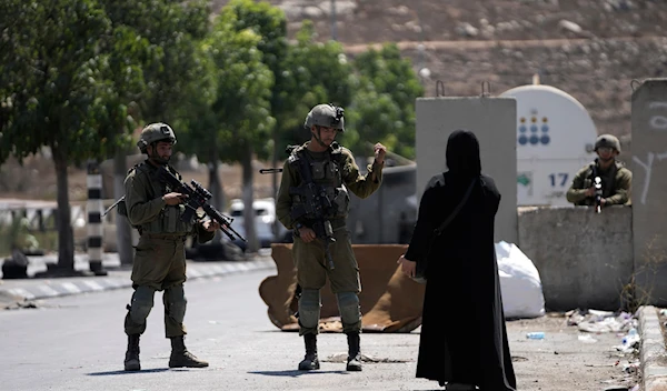 Israeli forces stand in the way of a Palestinian woman in an illegal settlement on Aug. 30, 2023. (AP)