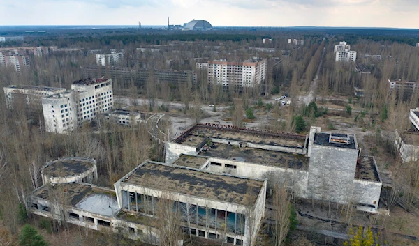 A view of the ghost town of Pripyat with a shelter covering the exploded reactor at the Chernobyl nuclear plant in the background, Ukraine, April 15, 2021 (AP)