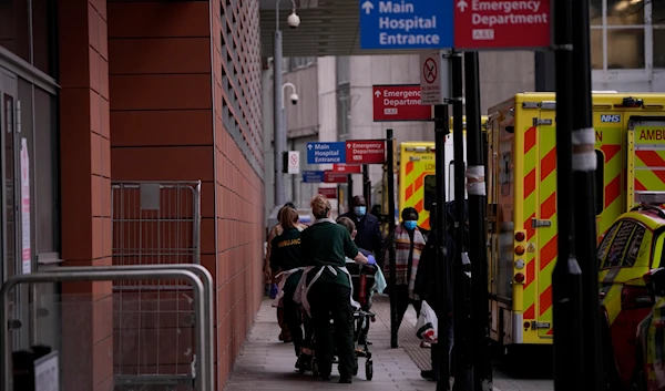 A patient is pushed on a trolley after arriving in an ambulance outside the Royal London Hospital in the Whitechapel area of east London, on January 6, 2022. (AP)