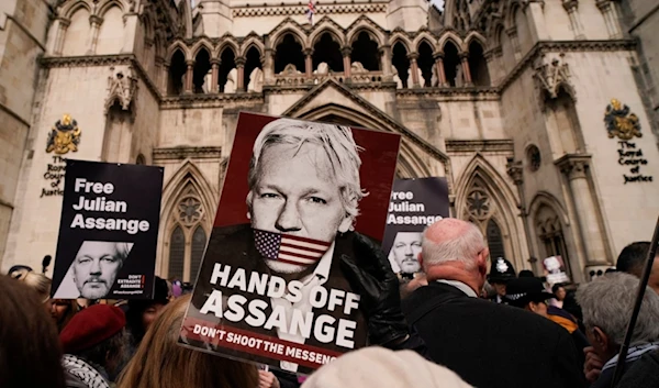 Demonstrators hold placards after Stella Assange, wife of Wikileaks founder Julian Assange, released a statement outside the Royal Courts of Justice, in London, Tuesday, March 26, 2024. (AP)