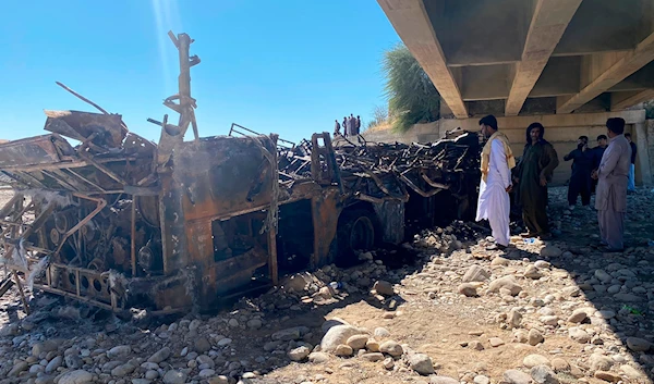 People look at the burnt wreckage of a bus accident in Bela, an area of Lasbela district of Balochistan province, Pakistan, Sunday, Jan. 29, 2023. (AP)