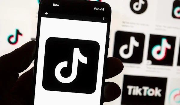 The TikTok logo is seen on a mobile phone in front of a computer screen which displays the TikTok home screen, Oct. 14, 2022, in Boston. (AP)