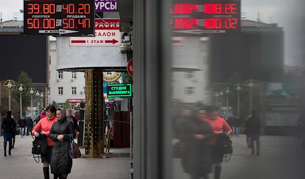 People walk past money exchange offices in Moscow, Russia, Monday, Oct. 6, 2014. (AP)