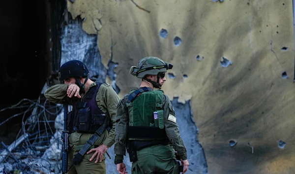 Israeli occupation forces walk past houses destroyed in Kibbutz "Be’eri", occupied Palestine, Saturday, Oct. 14, 2023. (AP)