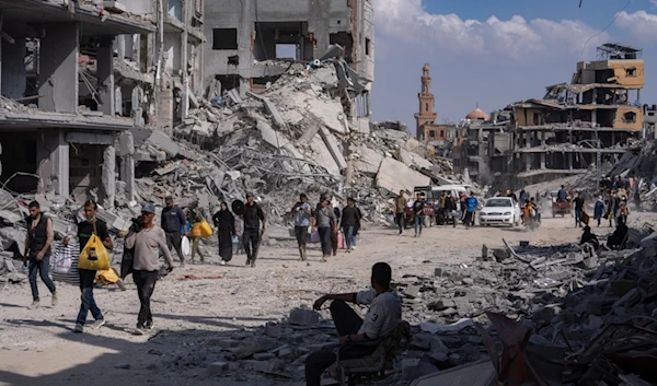 Palestinians walk through the destruction in the wake of an Israeli air and ground attack in Khan Younis, southern Gaza Strip, Monday, April 8, 2024 (AP Photo/Fatima Shbair)