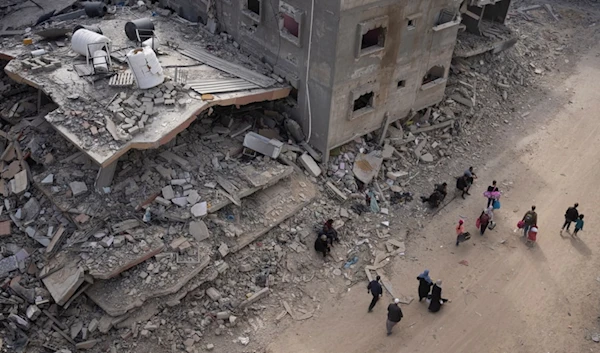 Palestinians walk through the destruction in the wake of an Israeli air and ground offensive in Khan Younis, southern Gaza Strip, Monday, April 8, 2024. (AP)