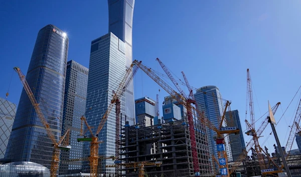 Construction cranes are seen at construction sites near office buildings of the main business district in Beijing, China, Saturday, March 30, 2024. (AP Photo/Tatan Syuflana)