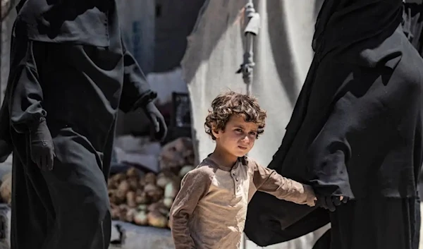 A woman walks with a child at the Western-backed SDF al-Hol camp in Hasakeh governorate in northeastern Syria, on June 23, 2021. (AFP via Getty Images)