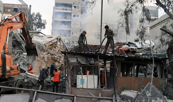 In this photo released by the official Syrian state news agency SANA, emergency service workers clear the rubble at the destroyed Iranian Consulate building struck by Israeli jets in Damascus, Syria, Monday, April 1, 2024 (SANA via AP)