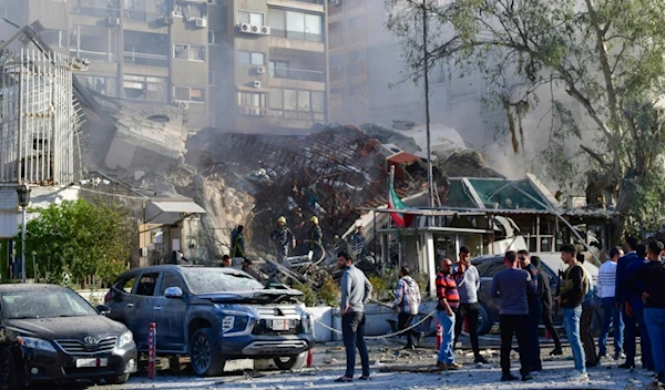 In this photo released by the official Syrian state news agency SANA, people gather near a destroyed building struck by Israeli jets in Damascus, Syria, Monday, April 1, 2024 (SANA via AP)