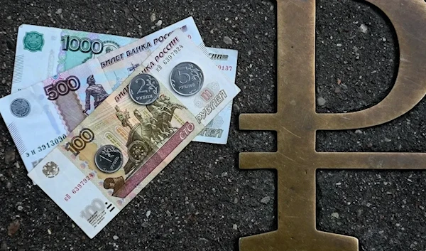 This picture taken on August 13, 2021, in Moscow, shows Russian ruble coins and banknotes pictured next to Russian ruble sign. (AFP)