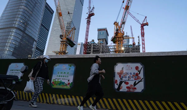 A man runs past construction cranes near the central business district in Beijing, on Tuesday, April 16, 2024.(AP)