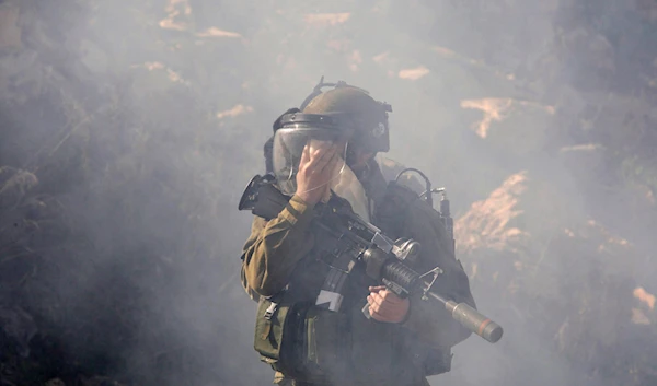 An IOF troop covers his face as he walks during clashes with Palestinian protesters,  near the West Bank city of Ramallah, Monday, Feb. 13, 2012. (AP)