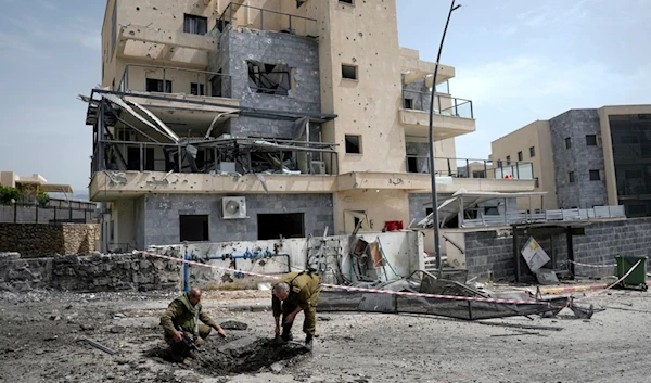 Israeli forces examine the site hit by a rocket fired from Lebanon, in Kiryat Shmona, northern occupied Palestine, Wednesday, March 27, 2024 (AP)