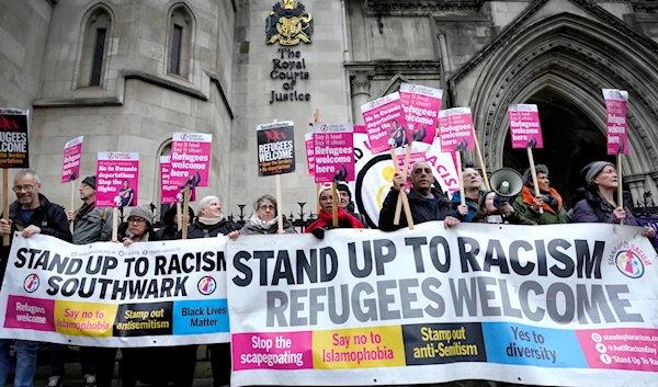 Stand Up To Racism campaigners hold banners outside the High Court in London, Monday, Dec. 19, 2022.(AP)