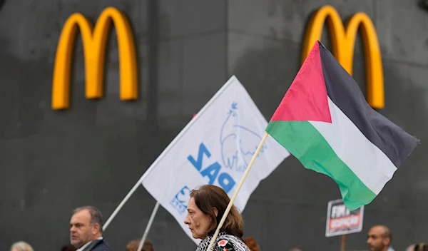 Protestors carrying a Palestinian flag and another with the word Peace walk past a McDonald's restaurant in Lisbon, Saturday, April 6, 2024.(AP)