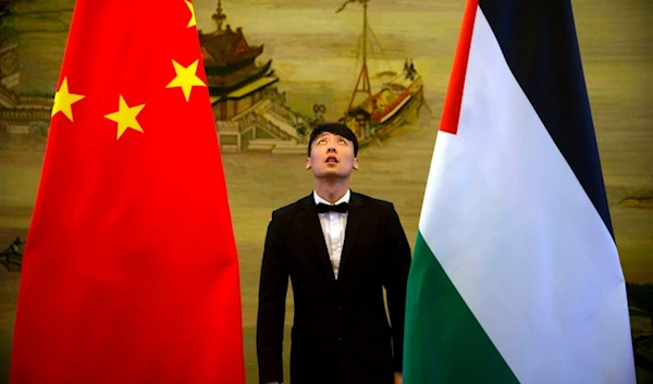 A staff member checks the alignment of Chinese, and Palestinian flags before the start of a joint press conference in Beijing, Thursday, April 13, 2017. (AP)