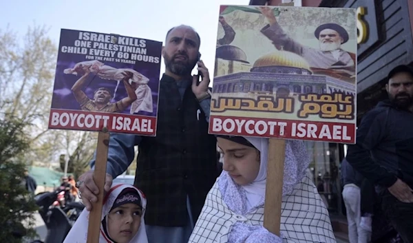 Kashmiri Muslim girls hold placards next to their father along a street to mark the International Quds Day, on April 5, 2024. (AFP)