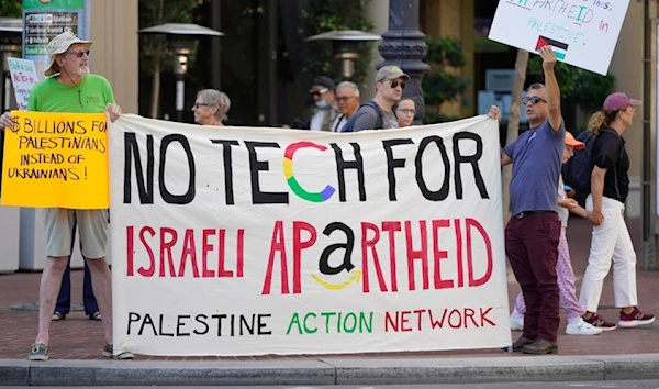 Two men hold up a banner and signs along Market Street during tech workers protest against Google and Amazon for their contracts with the Israeli occupation government in San Francisco, Thursday, September 8, 2022. (AP)