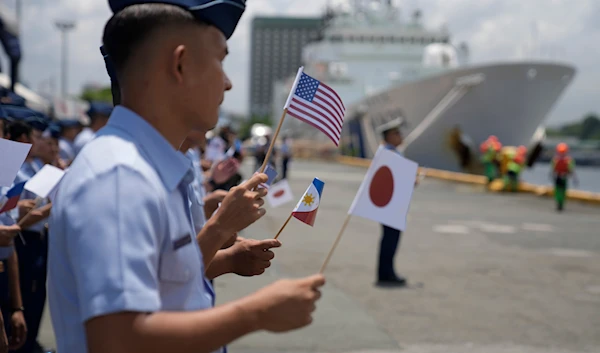 Philippine Coast Guard members wave small flags of the Philippines, U.S. and Japan during welcoming ceremonies at the pier in Manila, Philippines on Thursday, June 1, 2023. (AP)