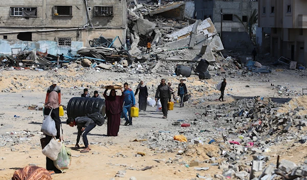 Palestinians walk through the destruction left by the Israeli aggression on Khan Younis, Gaza Strip, Friday, March 8, 2024. (AP)