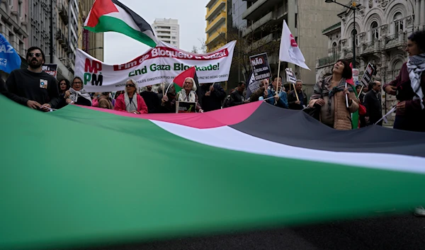 People carry a giant Palestinian flag while marching between the Embassy of 'Israel' and the Portuguese parliament in Lisbon demanding a ceasefire in Gaza and in support of Palestinians, Saturday, April 6, 2024. (AP)