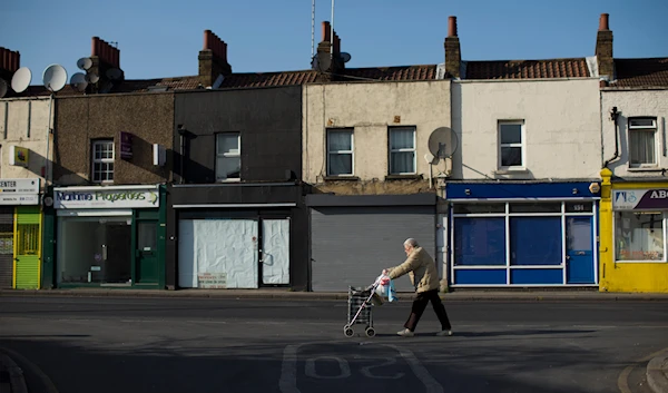 Britain High Street Lows** An elderly lady walks with a wheelie shopping bag past four closed shops on Trafalgar Road in Greenwich, London, Tuesday, March 5, 2013. (AP)